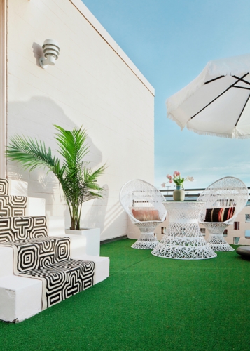 Không gian giải trí ngoài trời với ghế mây trắng và thảm xanh, ô che nắng kết hợp với cây cỏ tạo cảm giác thư thái nhất cho chủ nhà.
