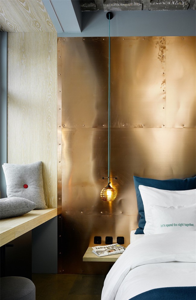 Pha trộn màu sắc lạnh và ấm là một ý tưởng hoàn hảo. Ở đây một bức tường đồng được kết hợp với bộ đồ giường bằng ngọc lục bảo và gối màu xám
