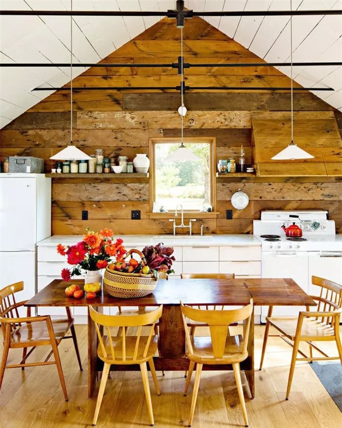 Bức tường ốp gỗ mộc mạc kết hợp liền mạch với các kệ nổi. Đồ nội thất bằng gỗ cũng làm tốt công việc phản ánh kiến trúc nên đứng trong nhà bếp này, bạn có cảm giác hòa quyện vào cả phòng ăn trang trọng.