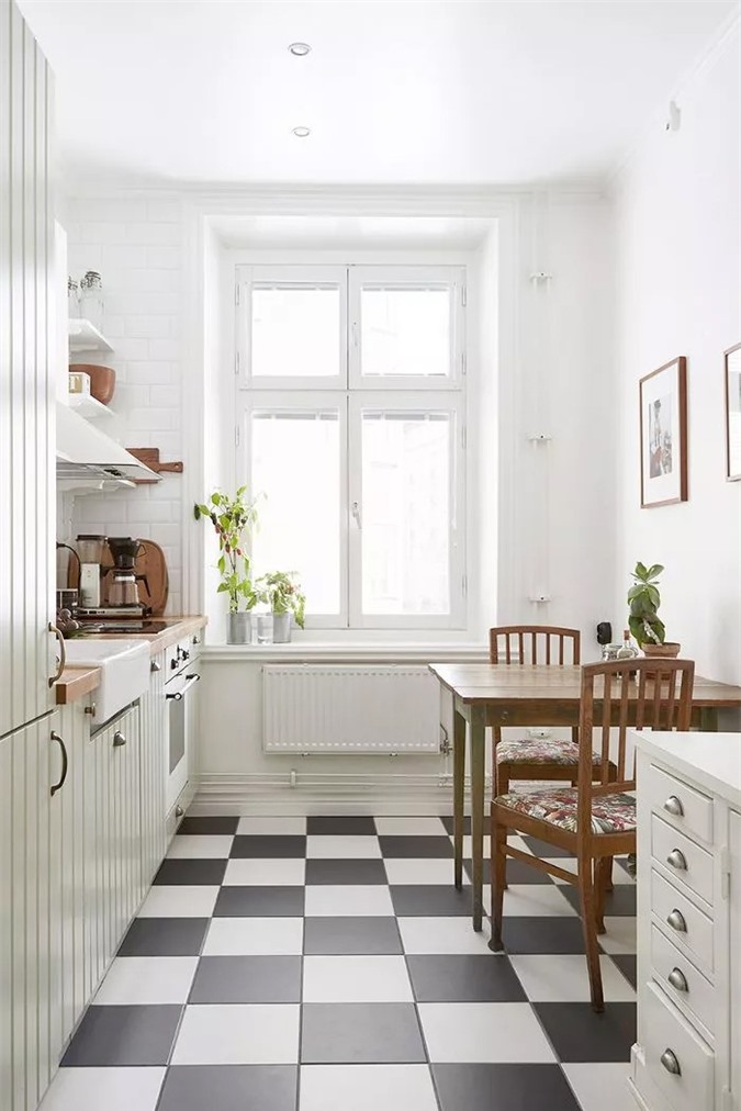 Nhà bếp nhỏ xinh này có rất nhiều thứ để yêu thích: kệ mở đơn giản, máy hút mùi không cầu kỳ, mặt bàn bằng gỗ mộc mạc, tủ gỗ màu xanh nước biển tuyệt đẹp và sàn lát gạch đen trắng cổ điển.