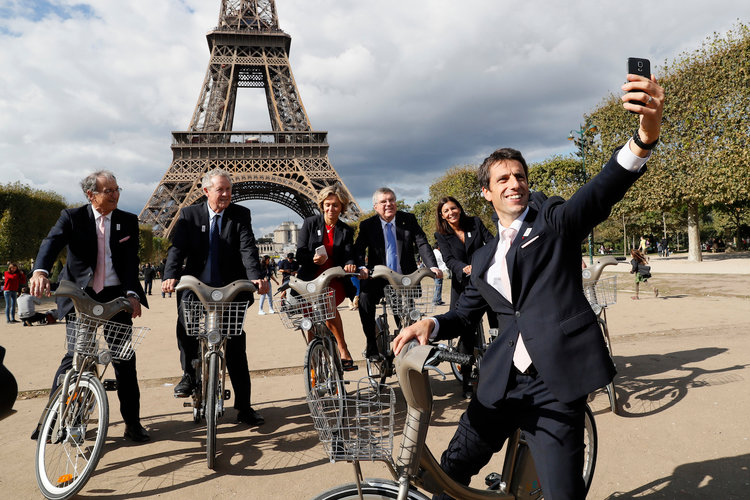 Ảnh: Nhà vô địch ca nô người Pháp và đồng chủ tịch của ứng cử viên Paris Tony Estanguet chụp ảnh tự sướng trên chiếc xe đạp Velib tại Champ de Mars ở Paris, Pháp / Nguồn © https://www.businessinsider.com/