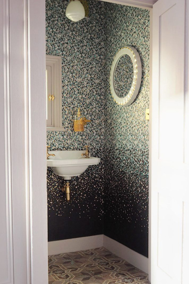 Một hình nền lấy cảm hứng từ sơn splatter vừa bổ sung và tương phản với gạch theo phong cách Địa Trung Hải cổ điển. Cùng với chiếc gương, hình nền mang đến cho phòng tắm nhỏ bé này một nét rất hiện đại