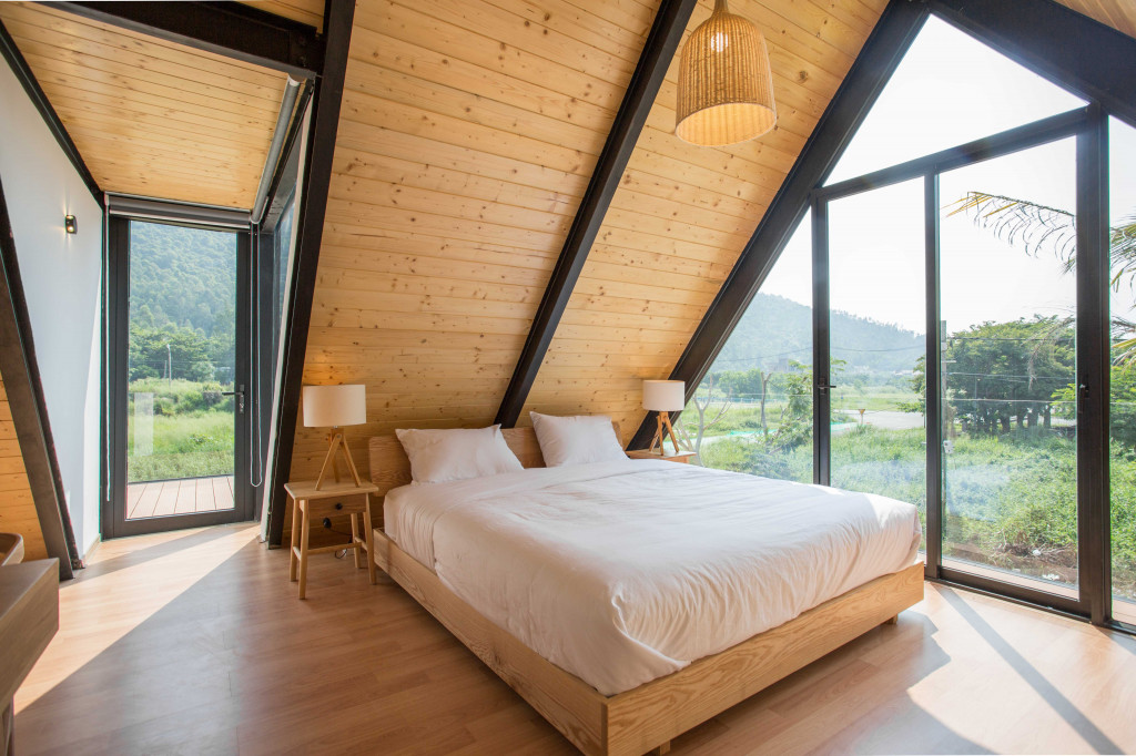 Không gian tầng áp mái làm phòng ngủ với hệ cửa kính mở, giúp gia chủ cảm nhận bầu không khí trong và ngoài