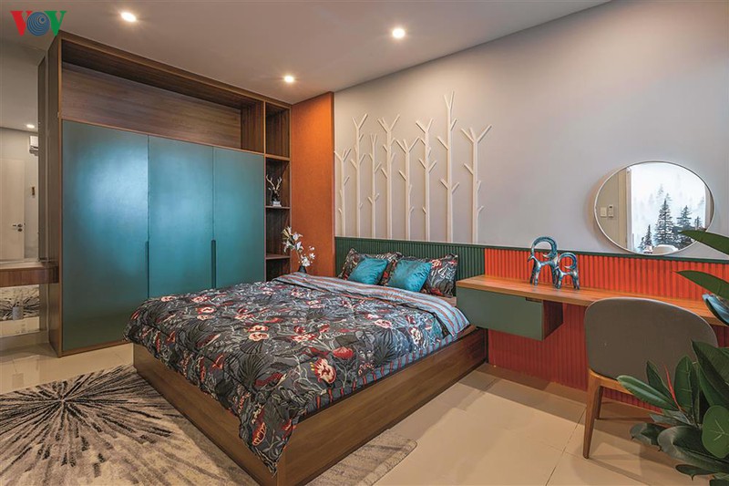 Phòng ngủ chính rộng rãi, với màu xanh và màu cam chủ đạo.