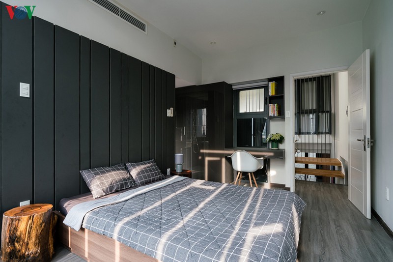 Một phòng ngủ khác nằm ở phía trước nhà. Mảng tường đầu giường được sơn màu xám sẫm, sàn gỗ màu xám nhạt.