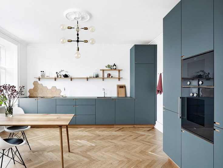 Phòng bếp kiểu Đan Mạch với tủ bếp màu xanh xám thiết kế tinh tế theo phong cách tủ đựng đồ, mang đến cảm giác ấm cúng. Tường chắn bếp (backsplash) lát bằng gỗ hình lục giác tạo điểm nhấn thú vị cho tường màu trắng.