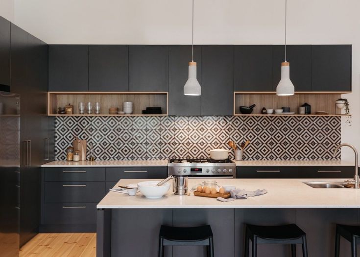 Tủ bếp làm bằng chất liệu gỗ được sơn đen mang đến nét mới lạ cho phòng bếp hiện đại. Tường chắn bếp lát gỗ họa tiết hình học nổi bật mang đến sự độc đáo cho không gian bếp.