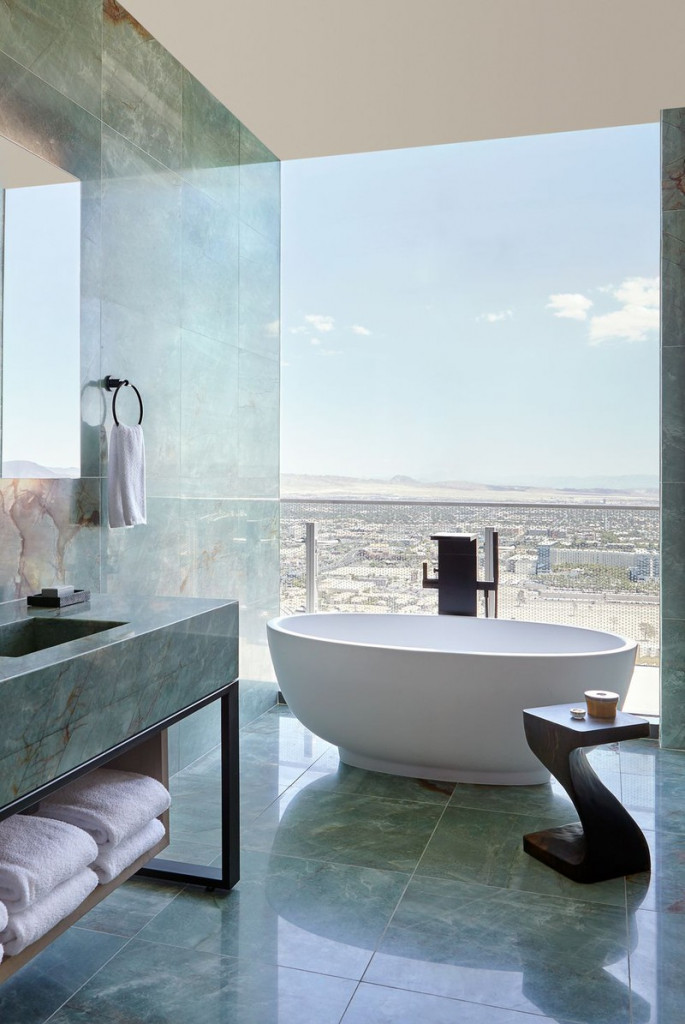 Nổi bật trên lớp đá cẩm thạch xanh lá và phần tường kính là bồn tắm oval