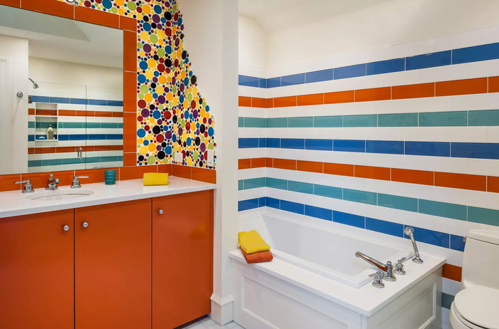 Gam màu rực rỡ giúp phòng tắm thêm ấm áp, trẻ trung và năng động. Sự kết hợp hài hòa giữa tường tông cam-xanh-trắng và đồ dùng màu trắng mang lại vẻ tươi mới và hiện đại.