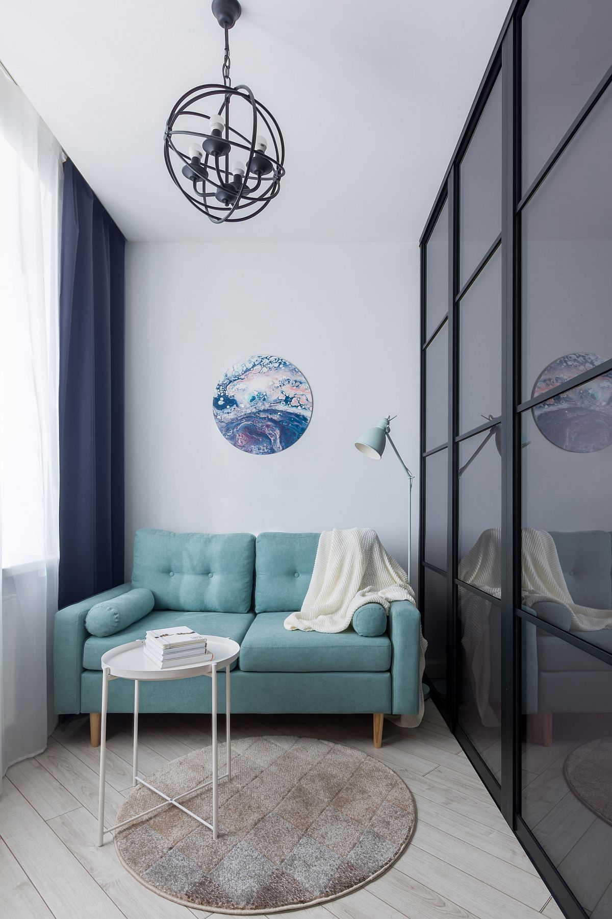 Phòng khách nhỏ với diện tích khá khiêm tốn nhưng vẫn vô cùng xinh xắn và đủ đầy khi được đặt sofa nhỏ gọn với màu xanh ngọc lam trẻ trung, bắt mắt