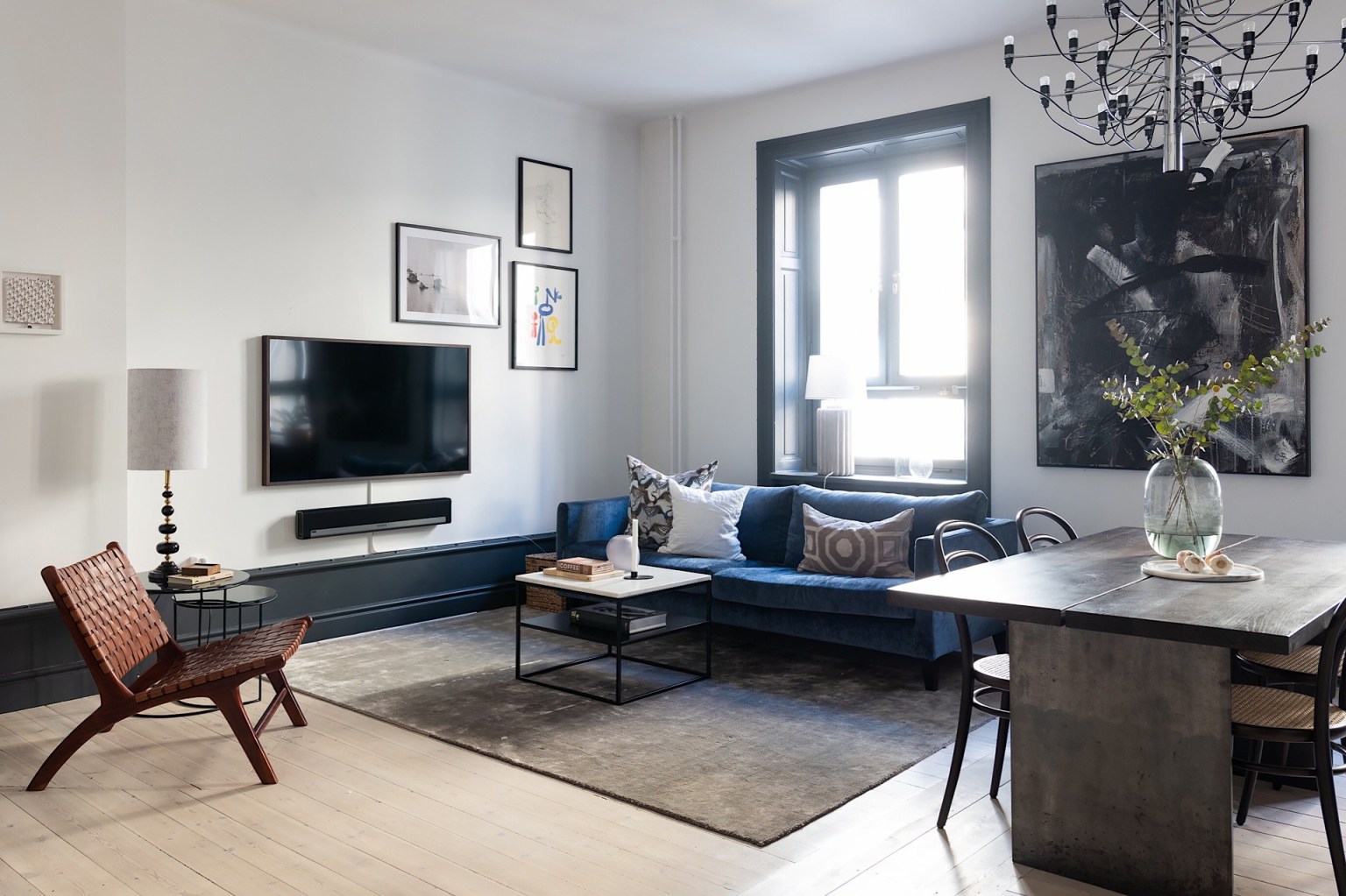 Sofa được lựa chọn màu xanh cổ vịt, sàn gỗ và tường màu trắng. Những màu nền tươi sáng giúp điểm nhấn trang trí màu đen thêm nổi bật sắc nét hơn.