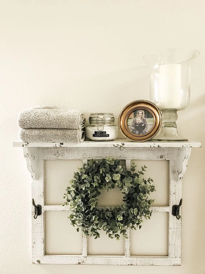 Một chiếc kệ từ khung cửa sổ cũ, với một vòng hoa được bện bằng cây xanh, một ngọn nến, một bức ảnh, và vài chiếc khăn là lý tưởng cho phòng tắm tinh tế.