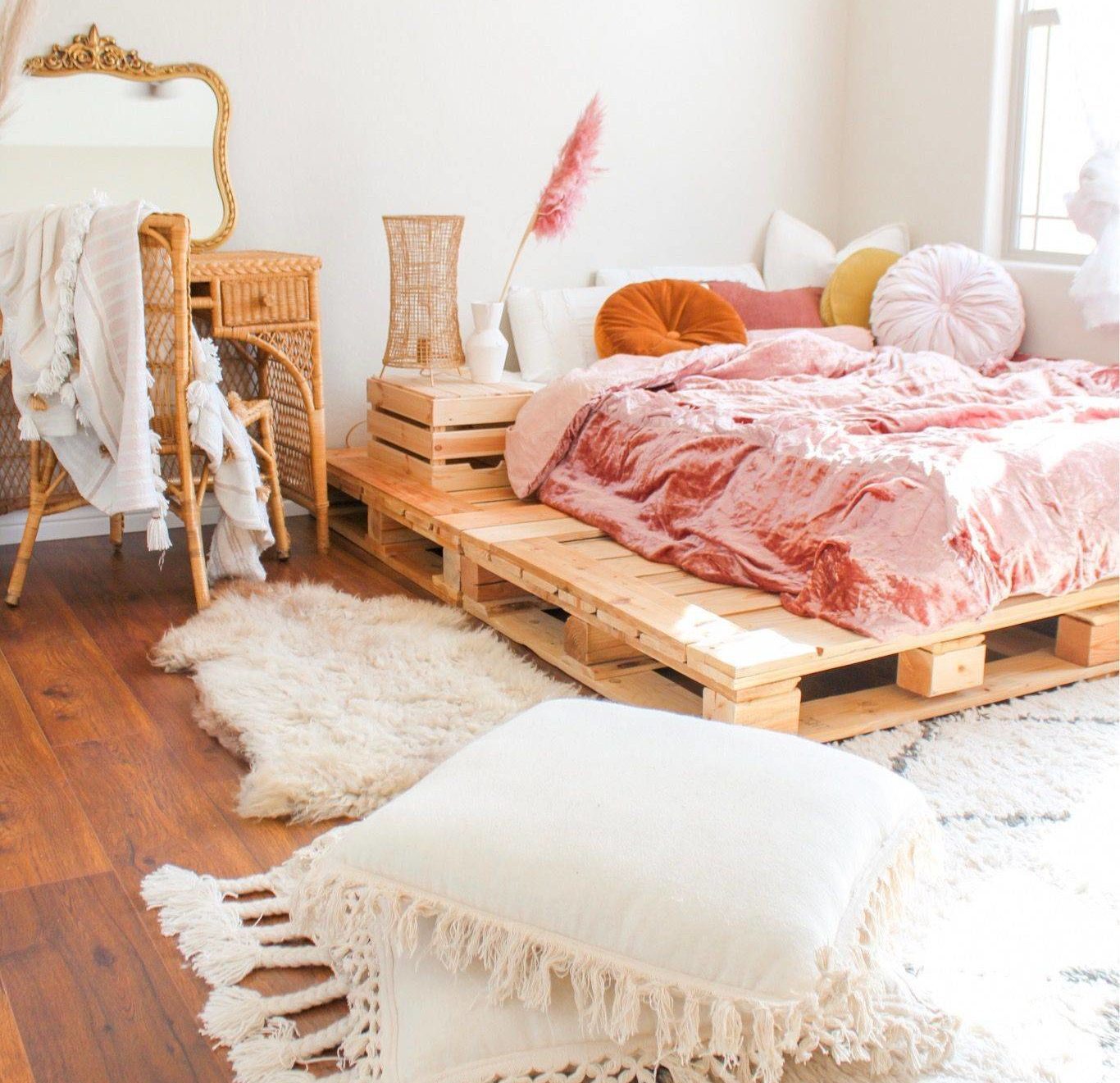 Bộ đồ giường bằng nhung nghiền màu hồng, tấm thảm lông giả và những chiếc gối có tua rua làm cho chiếc giường bằng ván pallet này trở thành một nơi ẩn náu thời thượng