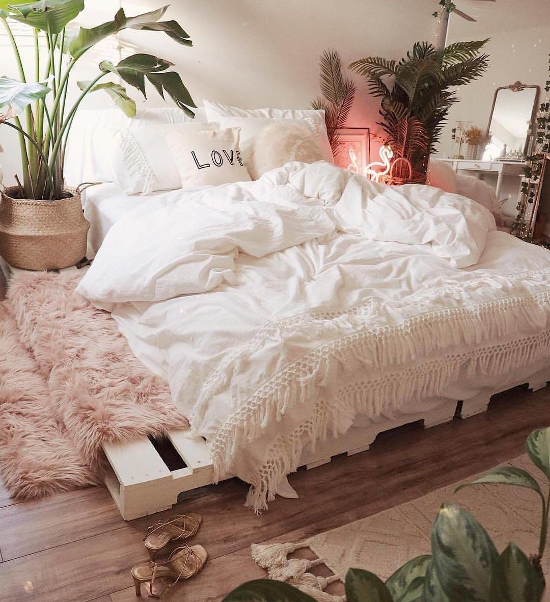 Phòng ngủ cực kỳ sang trọng này có giường pallet quét vôi trắng bên dưới chăn, thảm và tông màu hồng có họa tiết thơ mộng