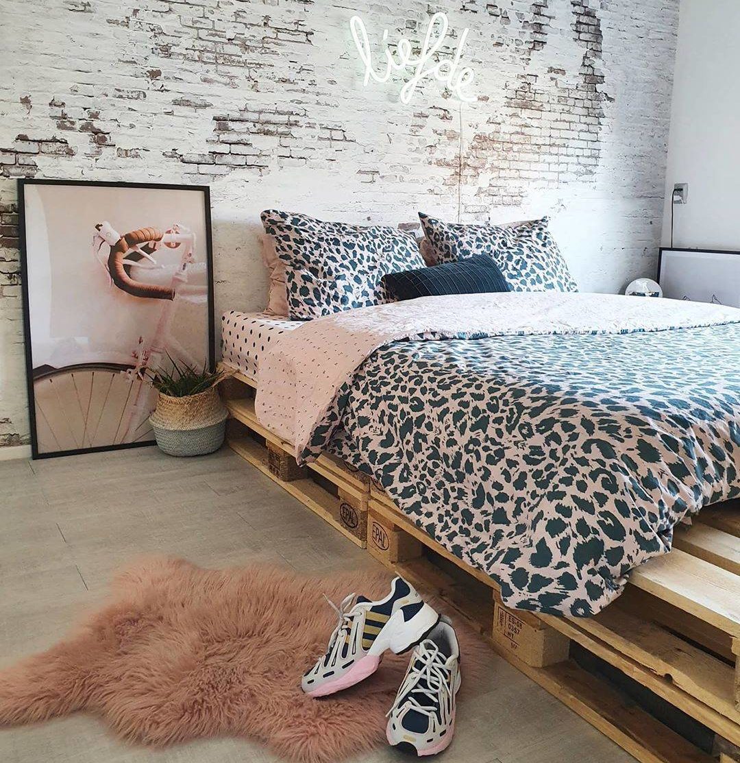 Một chiếc khăn trải giường in hình động vật, tấm thảm lông thú giả và tác phẩm nghệ thuật trên tường màu hồng giúp phòng ngủ trên giường pallet này trở nên nữ tính và quyến rũ