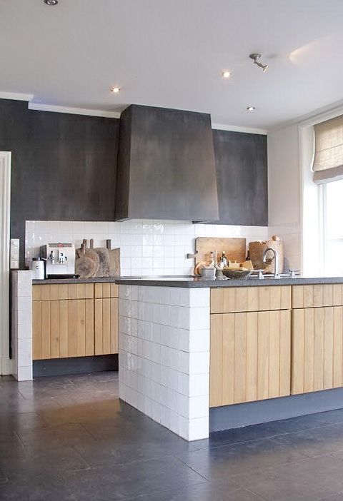 nhà bếp hiện đại với tủ gỗ màu sáng và mặt bàn bê tông, tường bê tông và máy hút mùi tích hợp rất sang trọng