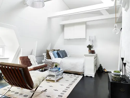 Căn hộ gác mái với nhiều nhược điểm như trần thấp, không vuông vắn được khắc phục với màu sơn trần, xà nhà, tường màu trắng.