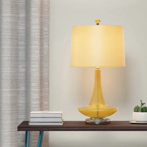 Thủy tinh màu vàng trong suốt và kết hợp với satin bóng tạo nên một chiếc đèn bàn sáng tạo mang lại nguồn ánh sáng rực rỡ như ánh sáng của mặt trời vào ban đêm