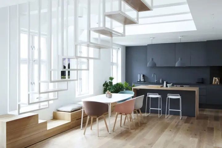 Bộ bàn ghế ăn màu pastel dịu nhẹ đặt bên dưới cầu thang mang đến nơi ăn uống nhẹ nhàng và thanh lịch