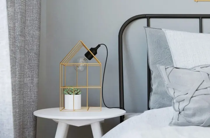 Đèn đầu giường được lồng vào khung sắt nơi chủ nhân còn trang trí thêm một chậu cây xinh xắn bên trong
