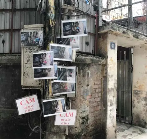 Gần chục bức hình người đổ rác trộm treo trên cây cột điện, tuy không rõ mặt nhưng khiến nhiều người e ngại không dám tái phạm. Ảnh: Lệnh Thắng