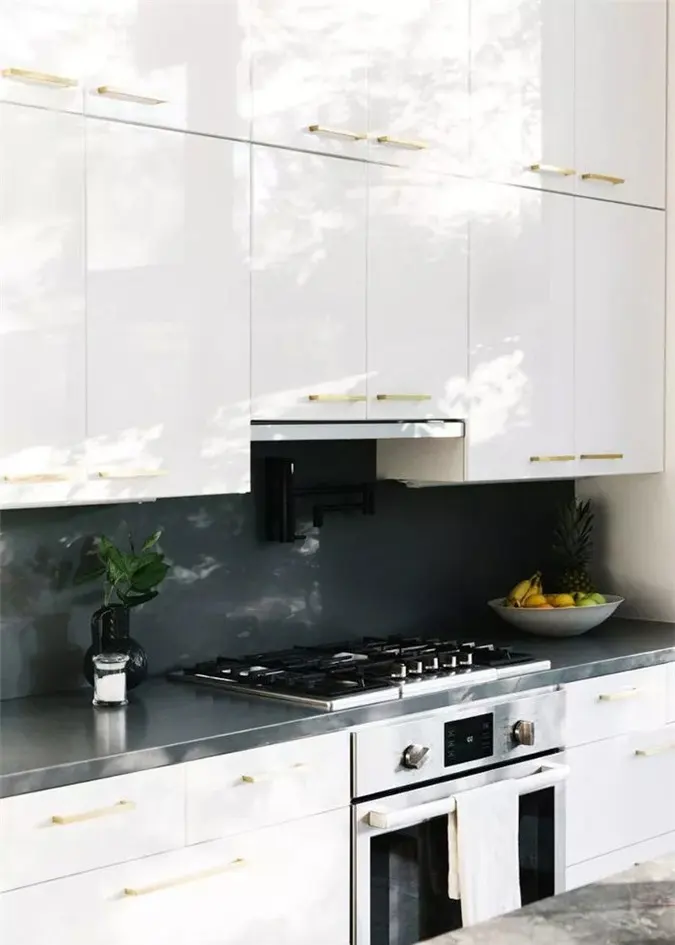 Nhà bếp này có thể nhỏ nhắn, nhưng các vật liệu xa xỉ như mặt bàn bằng đá cẩm thạch đen và lò nướng/bếp cao cấp, mang lại cho nó một hiệu ứng trang sức tốt. Trong những không gian hẹp như thế này, quá nhiều hoa văn hoặc màu sắc có thể bị áp đảo, vì vậy nhà thiết kế đã chọn cho tủ kem và chỉ cần một chút hoa văn trong một tấm thảm xương cá.