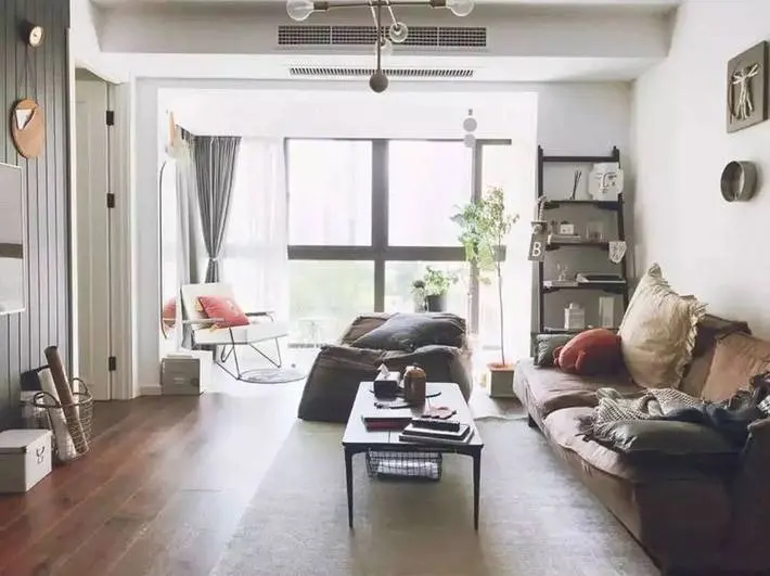 Phòng khách bày biện ít đồ trang trí, không gian cửa kính cường lực lấy ánh sáng tự nhiên từ bên ngoài