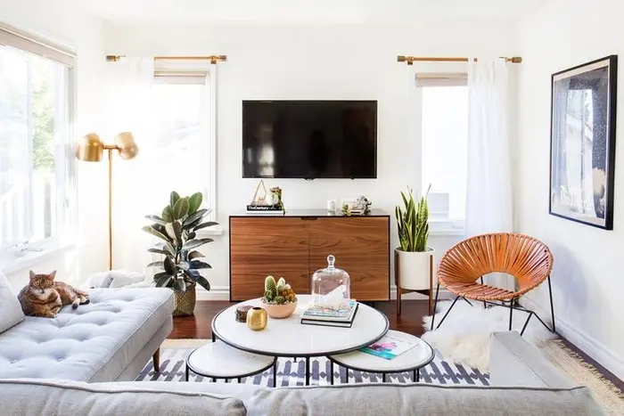 Ghế sofa hình chữ "L" tối giản là một cách tuyệt vời để tối đa hóa chỗ ngồi trong phòng khách nhỏ. Bộ bàn cà phê cùng chiếc ghế dệt bằng da vừa nhỏ gọn, sành điệu vừa không tốn nhiều diện tích. Các chậu cây mang lại sự cân bằng và vẻ đẹp cho căn phòng.