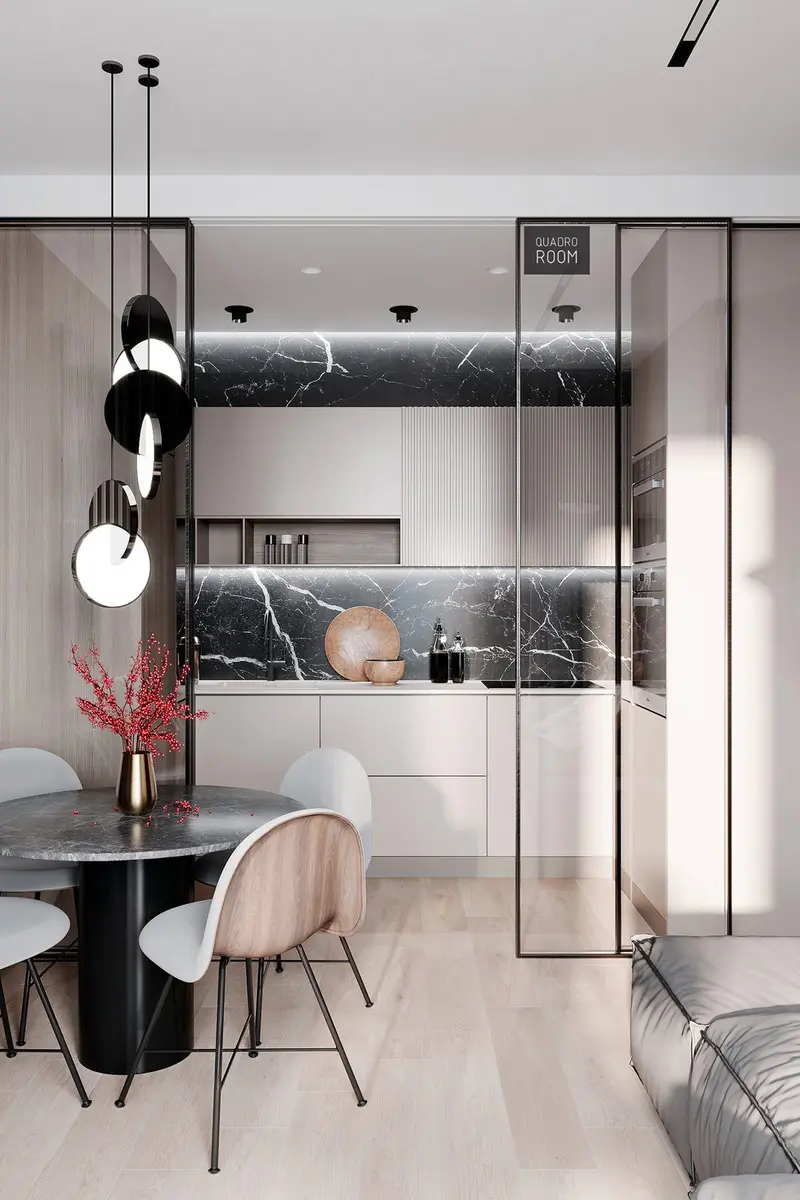 Một nhà bếp nhỏ được ngăn cách với phòng ăn và phòng khách bằng một bộ cửa kính trượt. Độ trong suốt của kính giúp không gian khiêm tốn dường như rộng hơn