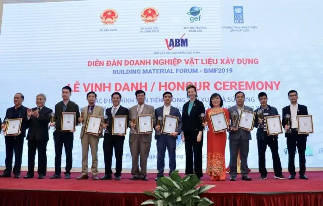 Thứ trưởng Bùi Phạm Khánh và bà Caitlin Wiesen trao giấy chứng nhận và cup tại lễ tôn vinh cho các điển hình tiên tiến trong sản xuất và sử dụng vật liệu xây không nung
