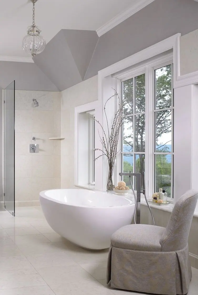 Trong không gian màu sắc khá trung tính với chiếc bồn oval màu trắng, bình hoa, chiếc ghế đệm màu xám giúp cân bằng và tạo cảm giác thư giãn