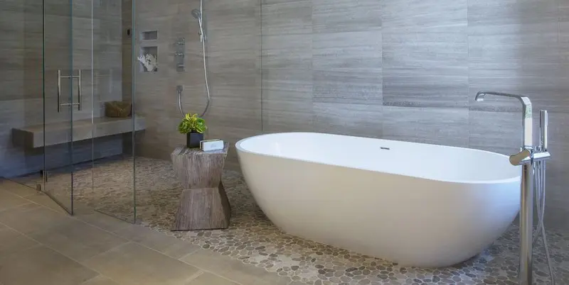 Thiết kế phòng tắm tối giản với chiếc bồn trắng làm nổi bật các vật liệu tự nhiên như tường gỗ, đôn gỗ và bình hoa nhỏ