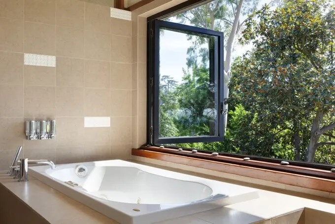 Bồn tắm bố trí gần cửa sổ hình khung đen cho phép gia chủ tận hưởng quang cảnh ngoài trời, không khí đầy nắng, mát mẻ.