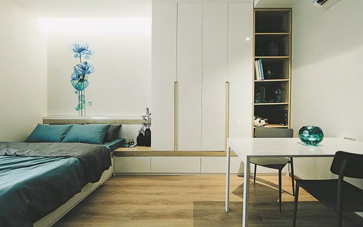 Tủ quần áo được bố trí ở phía đầu giường, cao sát trần để tận dụng không gian chứa đồ. Màu sắc nội thất sử dụng màu trắng điểm xuyết sắc xanh cho cảm giác rộng rãi và mát mẻ. Thiết kế loại bỏ những trang trí không cần thiết có thể gây rối mắt hay chật chội.