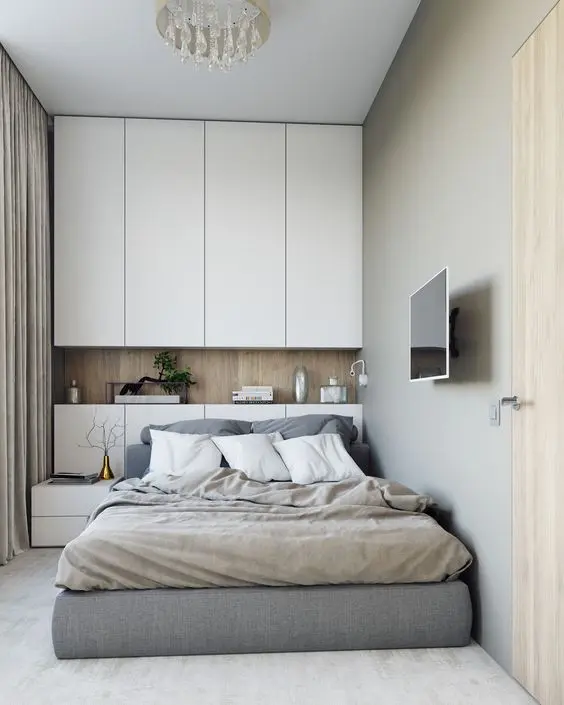 Nếu bạn muốn có một chiếc giường lớn thoải mái hơn trong phòng ngủ nhỏ, thì hãy thử cách trang trí theo ý tưởng của căn phòng này xem sao nhé. Đầu giường sẽ thiết kế tích hợp tab đầu giường và kệ để đồ trang trí cơ bản. Phía trên đầu giường, không gian được tận dụng thiết kế tủ quần áo cao sát trần, vừa tạo nên sự mới lạ, vừa giúp căn phòng thêm thoáng đãng và mới mẻ hơn.