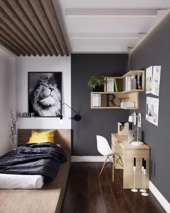 Căn phòng được decor khá nổi bật, bức tranh kết hợp với đèn ngủ treo tường ngay phía đầu giường, giường thiết kế dạng bệt khối gỗ, ga giường màu tối mang lại sự phức hợp nổi bật cho không gian nhỏ. Đối lập với nó là bàn học và kệ gỗ treo tường màu nâu gỗ vàng sáng, thiết ké tận dụng cắt góc giúp cân bằng những khoảng trống.