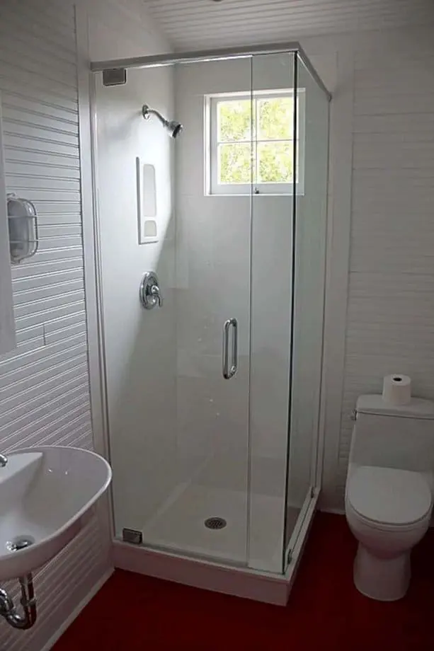 Phòng tắm nhỏ này đơn giản nhưng trông vẫn mát mẻ. Bạn có không gian rộng nhờ vách kính trong suốt thêm điểm nhấn đó là sàn trải thảm màu đỏ.