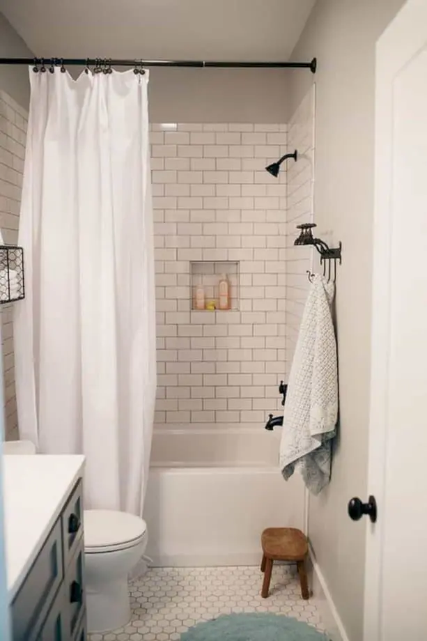 Điều làm phòng tắm nhỏ này trông đáng yêu là chiếc rèm màu trắng và gạch lát nền mosaic