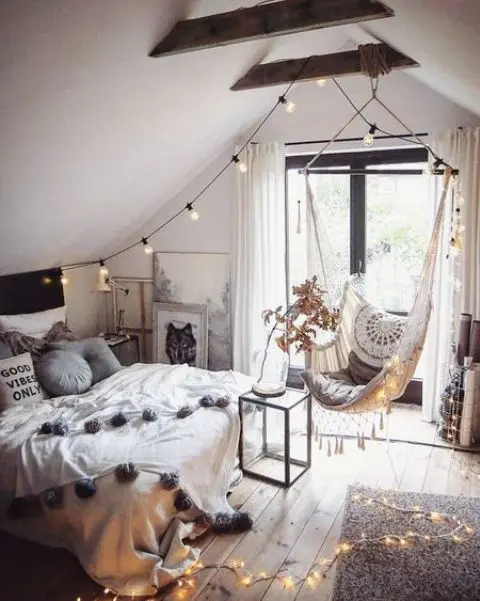 một căn phòng áp mái kiểu boho dành cho thanh thiếu niên với giường, ghế lơ lửng, đèn chiếu sáng và rất nhiều tác phẩm nghệ thuật là một không gian đáng yêu