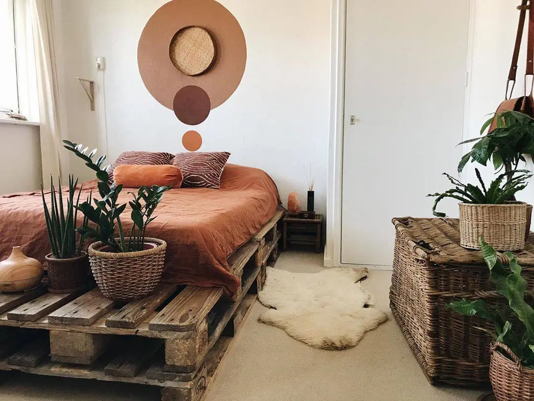 Tông màu đất Terra cotta và giỏ đan bằng liễu gai tôn lên chất gỗ tự nhiên mòn của khung giường pallet