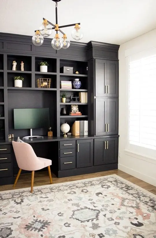 Không gian làm việc tại nhà ở trang trại hiện đại được trang bị tủ bếp màu đen, một chiếc ghế màu hồng, một chiếc đèn chùm cổ điển và những nét chấm phá bằng vàng