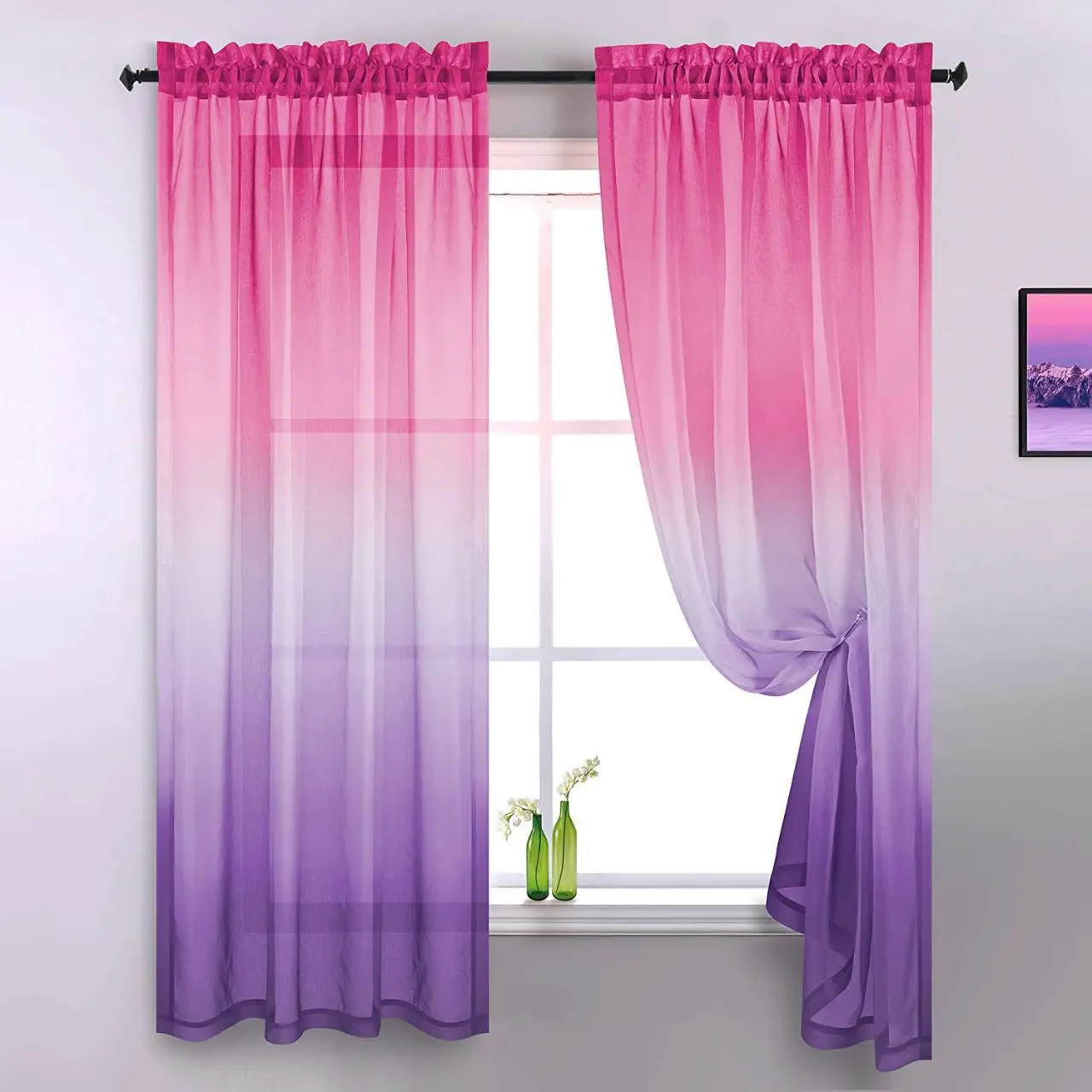 Lọ hoa thủy tinh xanh lá trên cửa sổ có rèm màu hồng và tím 